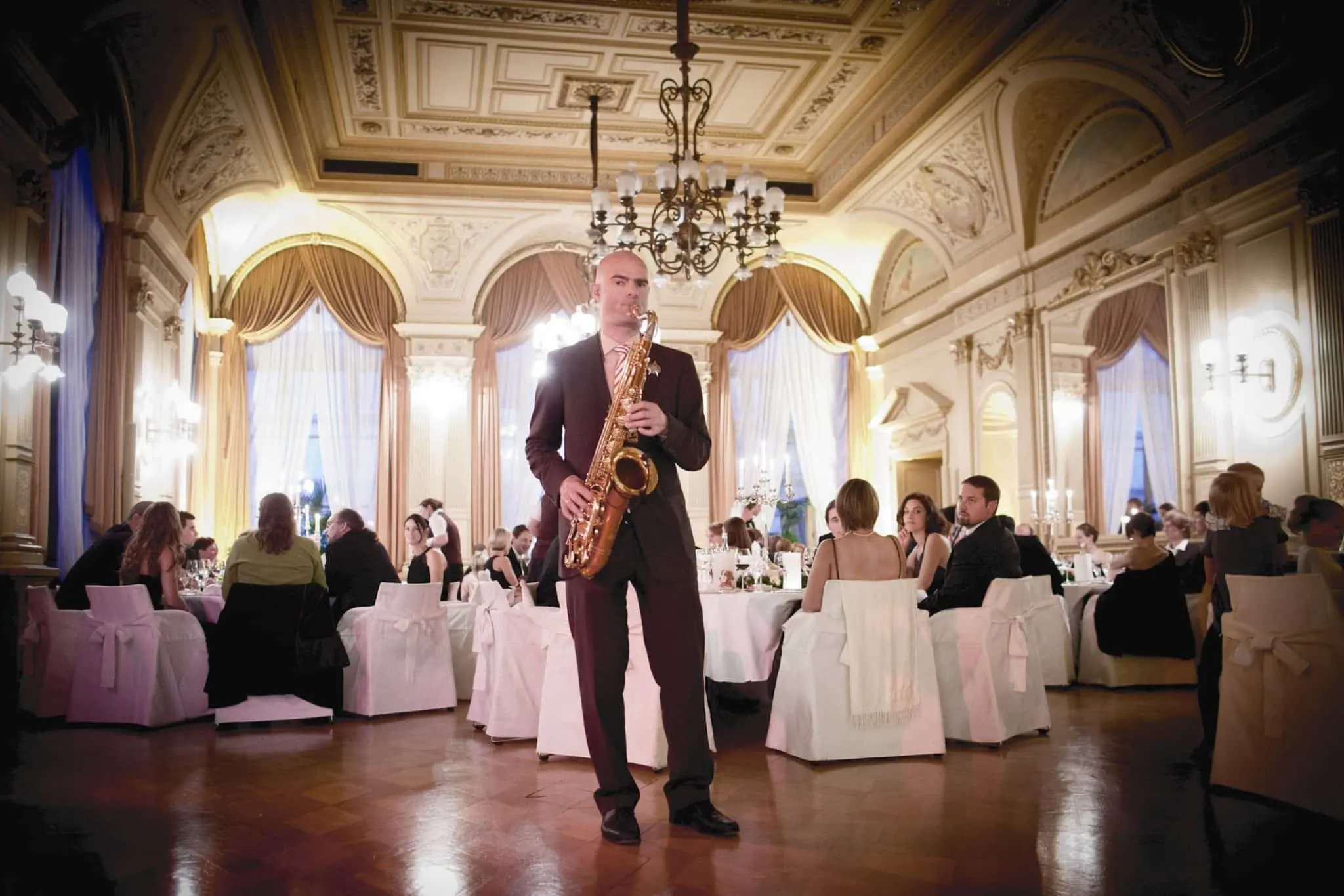 Sebastian Lilienthal spielt Saxophon im goldenen Ballsaal des Palais Prinz Carl Heidelberg vor festlich gedeckten Tischen